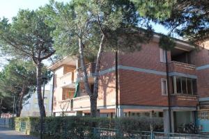 a red brick building with trees in front of it at Condominio ai bagni in Grado