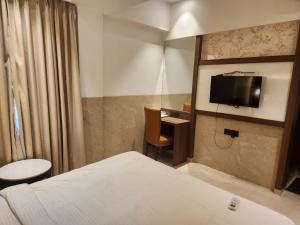 a hotel room with a bed and a desk and a tv at Hotel Suncity Residency in Kālundri
