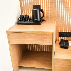 a wooden cabinet with a coffee maker on top of it at Hotel Mangla Inn - Dwarka in Dwarka