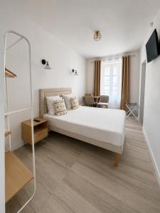 a white bedroom with a bed and a mirror at Hôtel JurJura in Dole