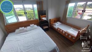 a bedroom with two beds and two windows at Open Kitchen Chiang Rai in Chiang Rai