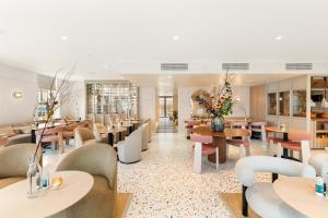 a restaurant with tables and couches and flowers at Hotel Bommeljé in Domburg