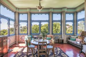 ein Wohnzimmer mit Tisch, Stühlen und Fenstern in der Unterkunft Chalet Saudade in Sintra