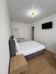 a white bedroom with a bed and a tv at Hôtel JurJura in Dole