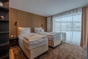 two beds in a room with a large window at Mama Boutique Apartment in Krušetnica