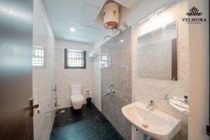 a bathroom with a sink and a toilet and a mirror at Velmora Luxe Residences in Madurai +9 photos