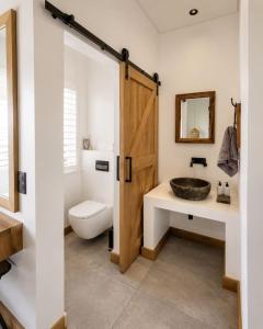 a bathroom with a sink and a toilet and a wooden door at Farmstead at ECS winery in Lake Marina +17 photos