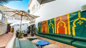 a patio with a couch and tables and an umbrella at Dar Lalzohra in Rabat