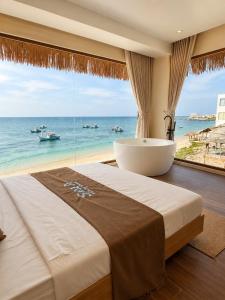 a bedroom with a large window with a tub and the ocean at Sala Beach Villa Phú Quý in Cù Lao Thu +38 photos