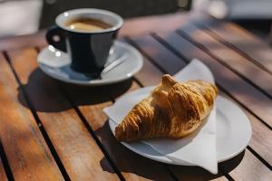 a croissant and a cup of coffee on a wooden table at Les 3 Vignobles in Pardaillan