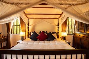 a bedroom with a canopy bed with red and blue pillows at Serenity Wellness in Kuruwita