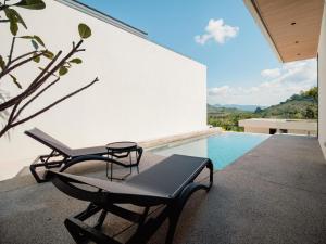 a patio with two chairs and a swimming pool at Villa Kauri 3BR Pool Villa at Aileen Naithon in Ban Sakhu