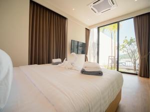 a bedroom with a large white bed with a large window at Villa Kauri 3BR Pool Villa at Aileen Naithon in Ban Sakhu