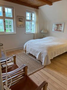 a bedroom with a bed and a chair and windows at Sølyst in Silkeborg