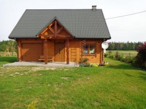 a wooden cabin in a field with a grass yard at U Witalisa in Narewka