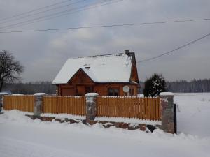 une maison en bois avec une clôture dans la neige dans l'établissement U Witalisa, à Narewka