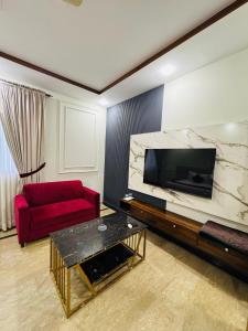 a living room with a red couch and a large television at Holiday One Hotel & Suites - Gulshan-4 in Karachi