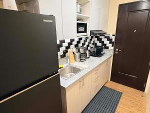 a kitchen with a sink and a black and white checkered wall at Penthouse Nook - Ananda square in Manila