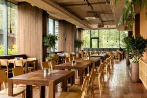 a restaurant with wooden tables and chairs and windows at ETERNA HOTEL & SPA by Fomich in Palyanytsya