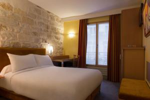 a bedroom with a large white bed and a stone wall at Hotel Danemark in Paris