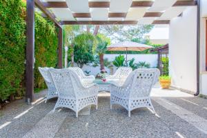 a patio with white wicker chairs and a table with an umbrella at Only Teens - Baia Verde in Baia Verde