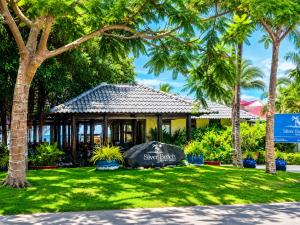 a building with a sign in the grass with palm trees at Silver Beach Resort Ke Ga in Ke Ga