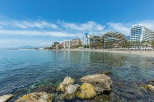 a beach with rocks in the water and buildings at Casa Alma Marbella in Marbella