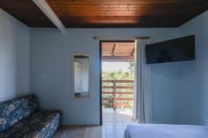 a living room with a couch and a sliding glass door at Hospedaria Nativa in Praia do Rosa