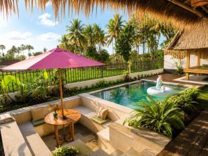 a swimming pool with an umbrella and a table and a table sidx sidx at JinengBali Eco Lodge in Tegalalang