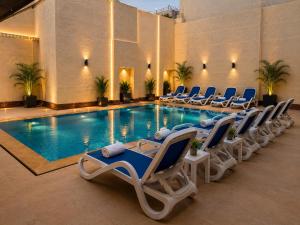 a pool with chaise lounge chairs and a swimming pool at Mamlouk Pyramids Hotel in Cairo