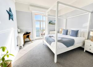 a white bedroom with a white canopy bed with blue pillows at A View Of The Bay- Close to Margate - Sleeps 3 in Westgate-on-Sea