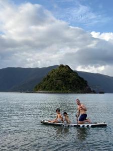 three people on a paddle board in the water at Ikada in Amami