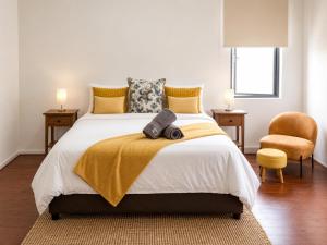 a bedroom with a bed with a yellow blanket and a chair at Musgrave Escape - 3 bedroom home with tennis court in Durban
