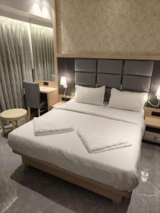 a bedroom with a large white bed and a desk at Hotel Suncity Residency in Kālundri