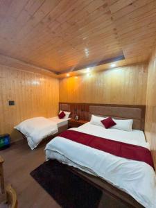 two beds in a room with wooden walls at Harshil wood stay in Harsil