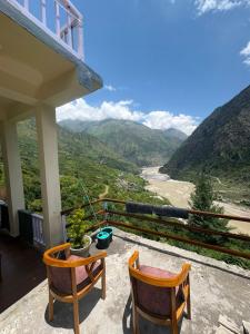 a balcony with two chairs and a view of a valley at Harshil wood stay in Harsil