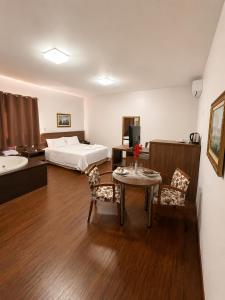 a hotel room with a bed and a table and chairs at CAMBRAIA HOTEL ARCOS in Arcos