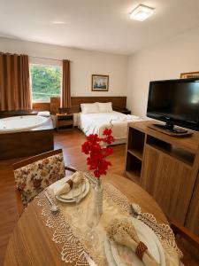 a room with a bed and a table with flowers on it at CAMBRAIA HOTEL ARCOS in Arcos