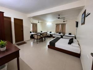 a hotel room with two beds and a table and chairs at BKR Resort in Kuttālam
