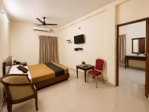 a bedroom with a bed and a tv and a chair at BKR Resort in Kuttālam