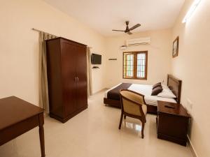 a bedroom with a bed and a table and a desk at BKR Resort in Kuttālam +51 photos