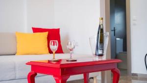 a red table with two glasses and a bottle of wine at Vickys Apartment Diakopto in Diakopto