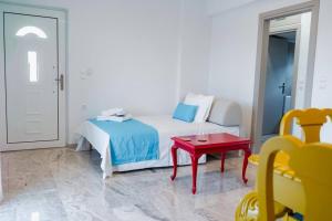 a white bedroom with a bed and a red table at Vickys Apartment Diakopto in Diakopto