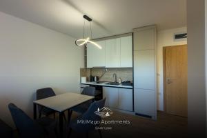 a kitchen with white cabinets and a table and chairs at Miti Apartment with Marina View & Spa Access in Veliko Gradište