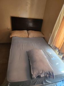 a bed in a small room with two pillows on it at Hidden Gem With Accomodation, Restaurant, Bar & Spa in Nairobi +4 photos