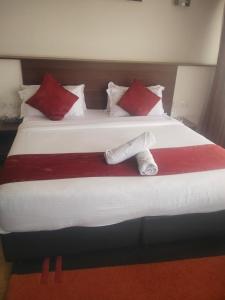 a large bed with red and white pillows at Hidden Gem With Accomodation, Restaurant, Bar & Spa in Nairobi