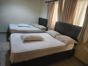 three twin beds in a room with windows at Hidden Gem With Accomodation, Restaurant, Bar & Spa in Nairobi