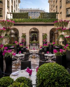 a patio with tables and chairs and flowers at Four Seasons Hotel George V Paris in Paris