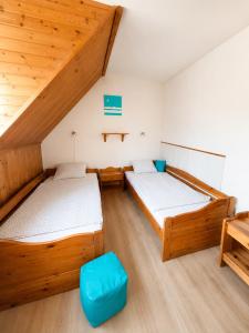 two beds in a room with wooden ceilings at Pákász Nyaralóház in Tiszafüred