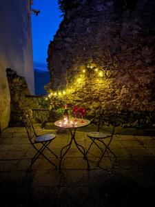a table with two chairs and lights on a stone wall at Guest House Villa Castello in Nucetto